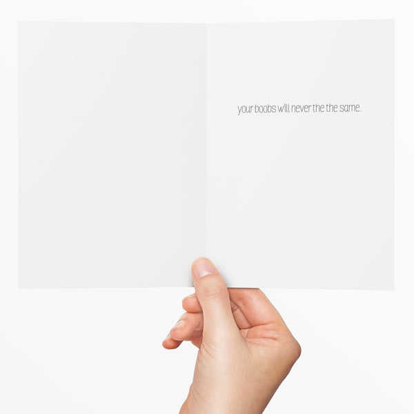 inside of new baby greeting card "Your boobs will never be the same" with a woman's hand holding the card.